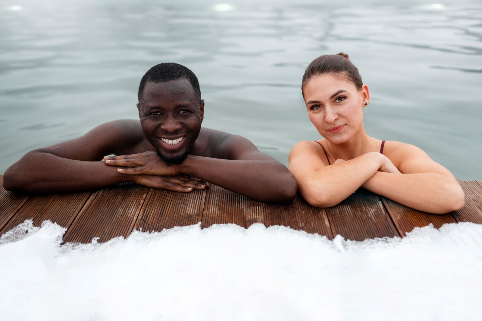 Twee mensen ontspannen in een verfrissend ijsbad, leunend op een houten platform