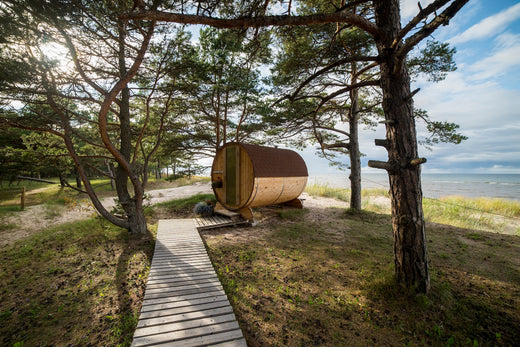 Buitensauna aan een strand, met uitzicht op de zee en omgeven door bomen en zandgrond